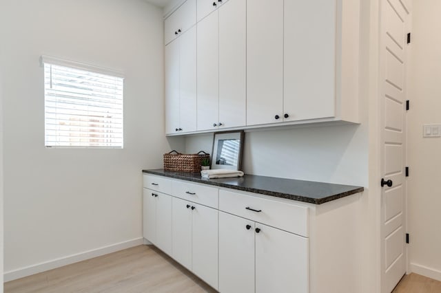 kitchen featuring white cabinets, light hardwood / wood-style floors, and dark stone counters