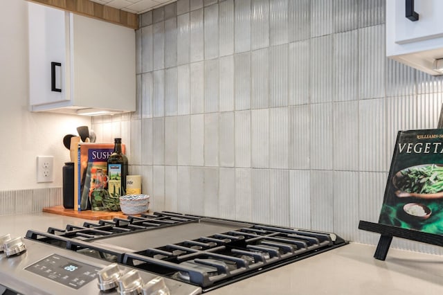 kitchen with tasteful backsplash, cooktop, and white cabinets