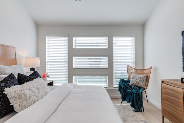 bedroom with light hardwood / wood-style floors and multiple windows