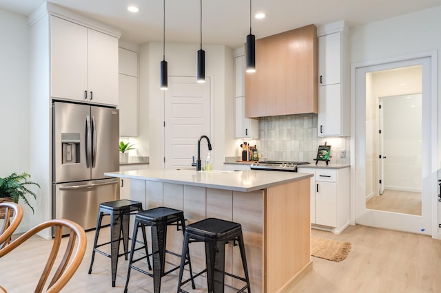 kitchen with a kitchen island with sink, backsplash, white cabinets, stainless steel fridge with ice dispenser, and light wood-type flooring