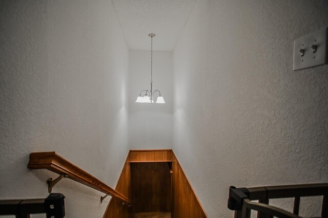 stairway with a notable chandelier