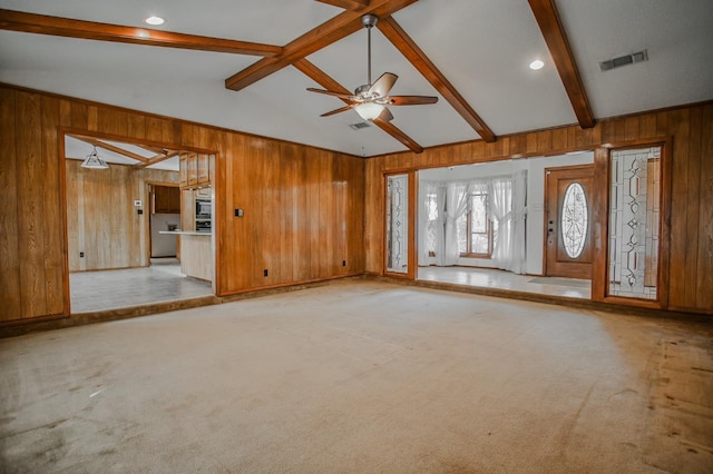 unfurnished living room with light carpet, vaulted ceiling with beams, ceiling fan, and wood walls