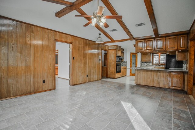 kitchen featuring backsplash, vaulted ceiling with beams, wooden walls, black appliances, and kitchen peninsula