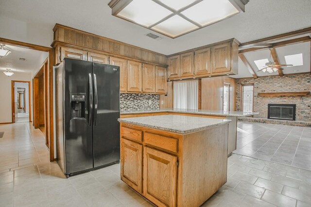 kitchen featuring black fridge, a skylight, kitchen peninsula, a kitchen island, and ceiling fan