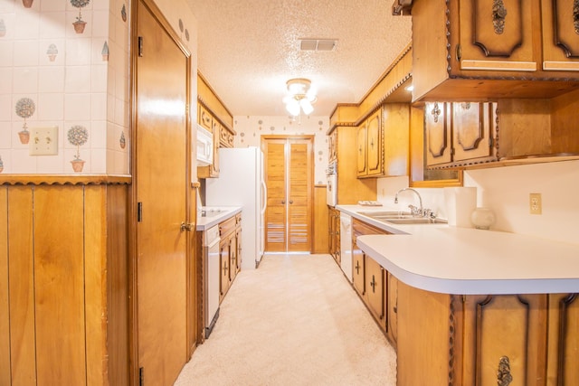 5720 71st St, Lubbock, TX 79424 - kitchen featuring a textured ceiling, white appliances, brown cabinetry, light countertops, and light carpet