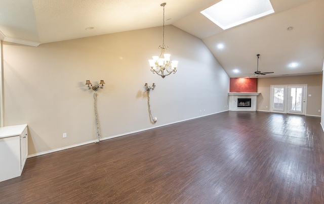 unfurnished living room with lofted ceiling with skylight, a fireplace, dark wood finished floors, and ceiling fan with notable chandelier