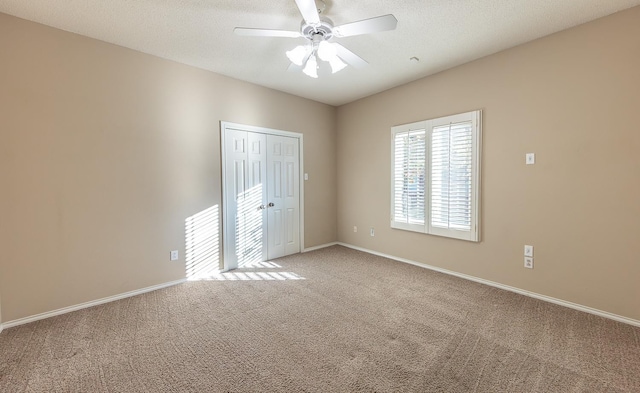 unfurnished room with carpet flooring, ceiling fan, a textured ceiling, and baseboards