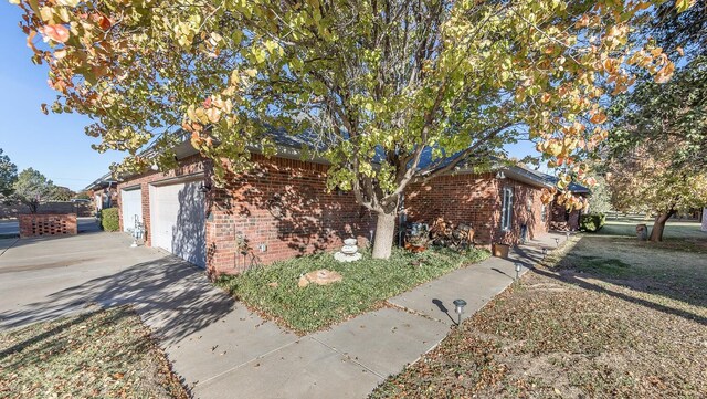 view of front facade with an attached garage, driveway, and brick siding