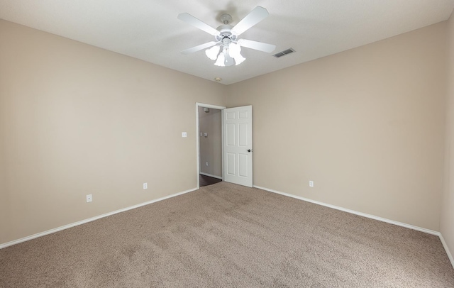 spare room with carpet floors, visible vents, baseboards, and a ceiling fan