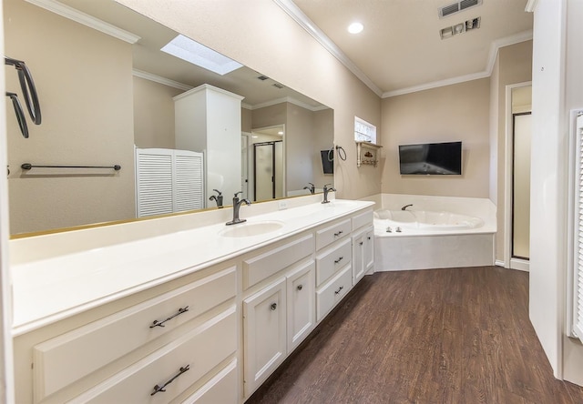 full bath featuring a skylight, a garden tub, crown molding, a sink, and wood finished floors