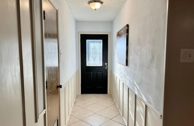 doorway to outside featuring a textured ceiling and light tile patterned flooring