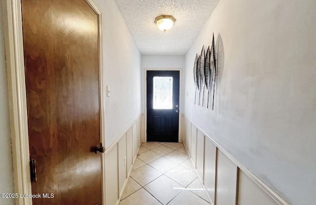 7907 Knoxville Ave, Lubbock, TX 79423 - doorway featuring a textured ceiling, a decorative wall, wainscoting, and light tile patterned flooring