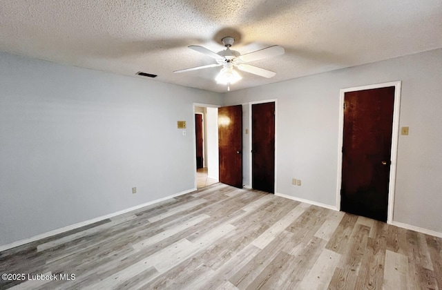 7907 Knoxville Ave, Lubbock, TX 79423 - unfurnished bedroom featuring light wood finished floors, a textured ceiling, baseboards, ceiling fan, and two closets