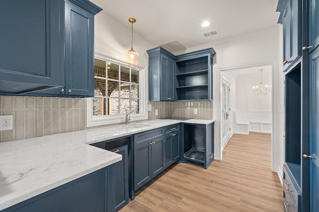 kitchen with sink, decorative backsplash, blue cabinets, decorative light fixtures, and light wood-type flooring