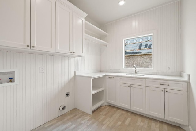 laundry room with sink, light hardwood / wood-style flooring, cabinets, washer hookup, and hookup for an electric dryer