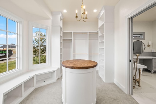 walk in closet with light colored carpet and a chandelier