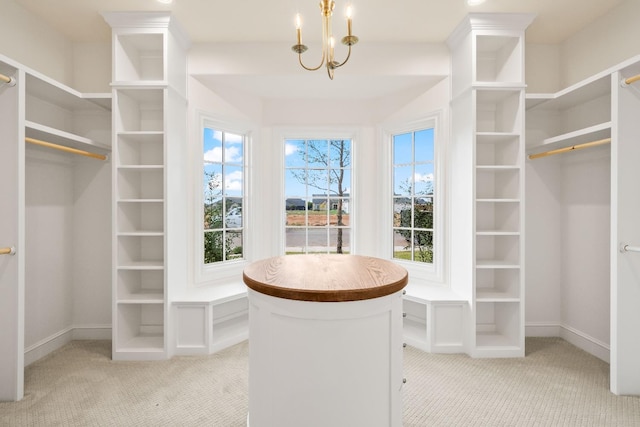 spacious closet with a notable chandelier and light colored carpet