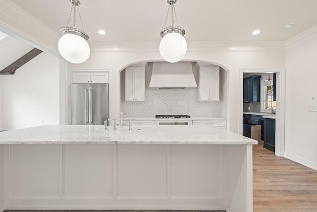 kitchen featuring light stone countertops, decorative light fixtures, high end refrigerator, and wall chimney exhaust hood