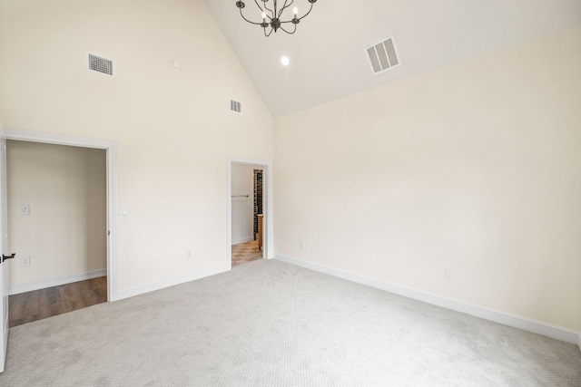 unfurnished room with a notable chandelier, light colored carpet, and high vaulted ceiling