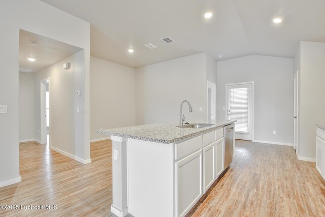 2012 Kenwood Ave, Lubbock, TX 79407 - kitchen featuring dishwasher, light wood-style floors, light stone countertops, white cabinets, and a kitchen island with sink