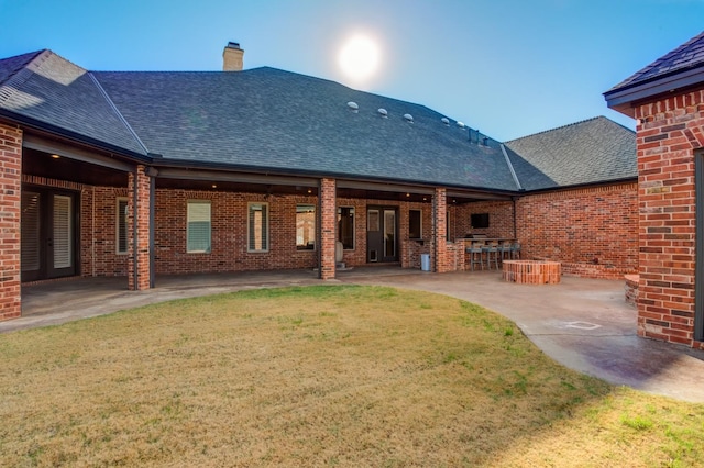 back of property with a yard, a bar, and a patio area