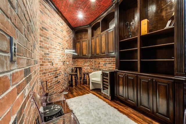 interior space featuring crown molding, brick wall, wine cooler, and dark hardwood / wood-style flooring