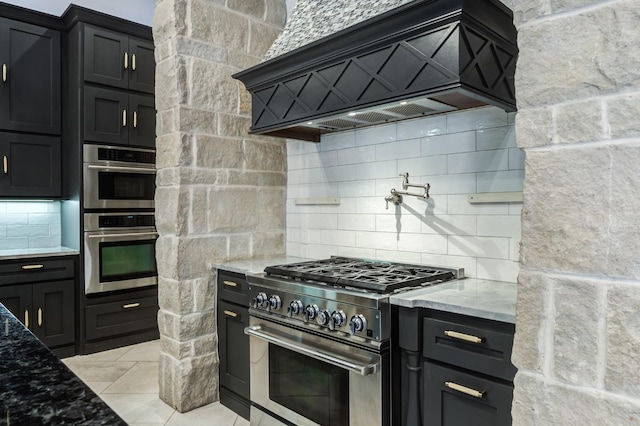 kitchen with stainless steel appliances, premium range hood, light stone countertops, and decorative backsplash