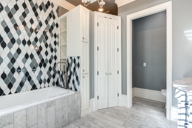 bathroom featuring a relaxing tiled tub, toilet, and crown molding