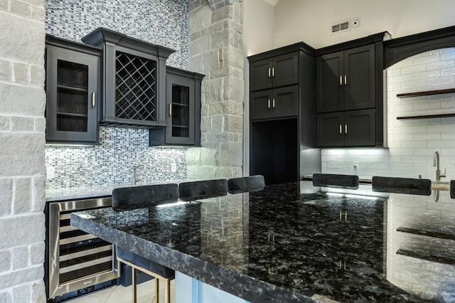 kitchen featuring tasteful backsplash, a breakfast bar, light tile patterned floors, and beverage cooler