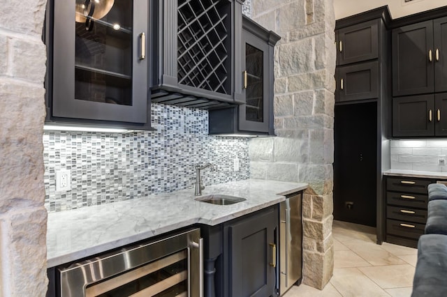 kitchen with wine cooler, sink, light stone counters, light tile patterned floors, and decorative backsplash