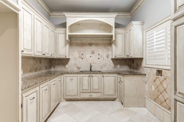 kitchen featuring stone countertops, sink, crown molding, and decorative backsplash