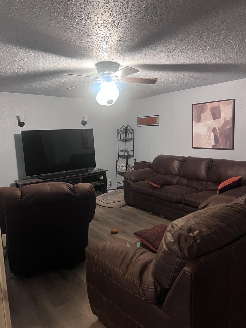 living room with a textured ceiling, wood-type flooring, and ceiling fan