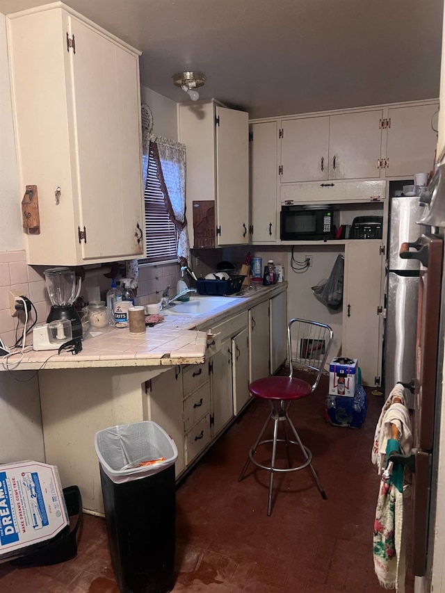 kitchen featuring sink, tile counters, and white cabinets