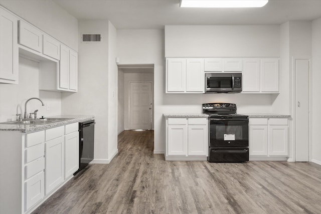 kitchen featuring white cabinetry, sink, light hardwood / wood-style floors, and black appliances