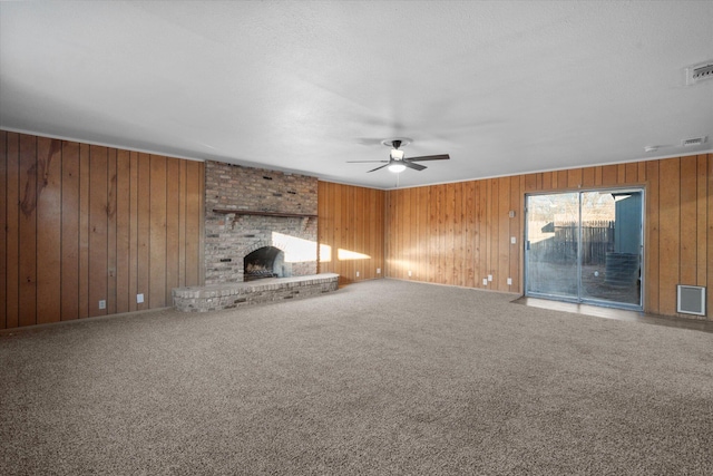 unfurnished living room with ceiling fan, a brick fireplace, carpet, and wooden walls