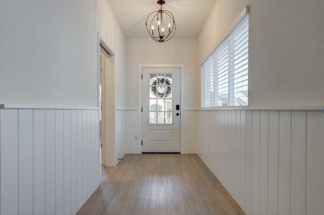 doorway to outside with an inviting chandelier and light hardwood / wood-style flooring