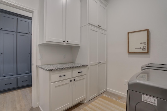 washroom with washer / clothes dryer, cabinets, and light hardwood / wood-style flooring