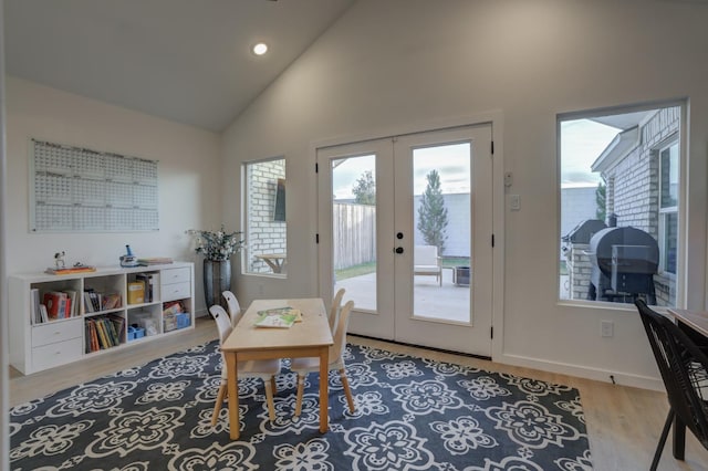 doorway to outside with high vaulted ceiling, light wood-type flooring, and french doors