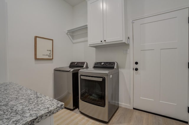 washroom with separate washer and dryer, light hardwood / wood-style floors, and cabinets