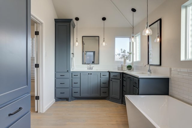 bathroom with vaulted ceiling, vanity, a bath, and hardwood / wood-style floors