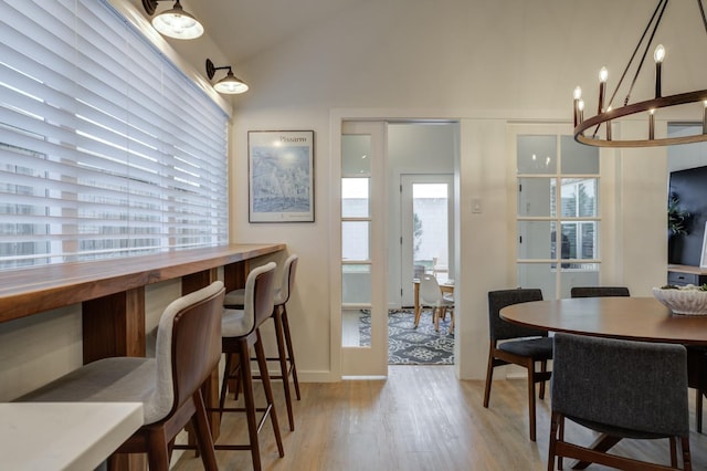 dining room featuring vaulted ceiling, light hardwood / wood-style flooring, and a wealth of natural light