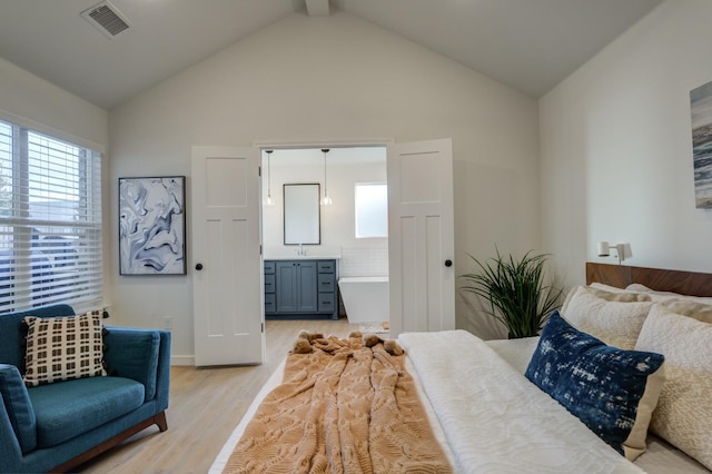 bedroom with vaulted ceiling, ensuite bathroom, and light wood-type flooring