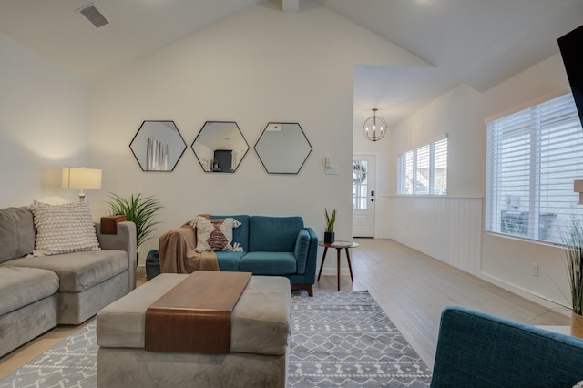 living room with lofted ceiling, a notable chandelier, and light hardwood / wood-style flooring