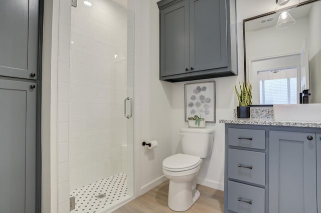 bathroom featuring hardwood / wood-style flooring, vanity, toilet, and a shower with door