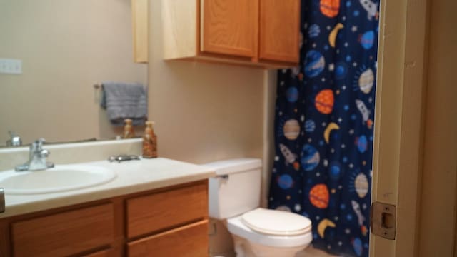 bathroom featuring vanity, walk in shower, and toilet