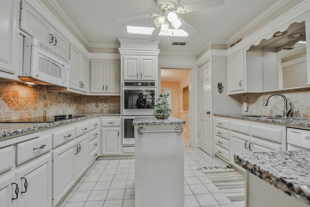 kitchen featuring sink, white appliances, light tile patterned floors, white cabinetry, and light stone countertops