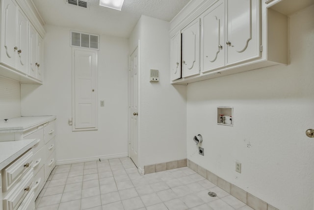 washroom with washer hookup, light tile patterned floors, cabinets, and a textured ceiling