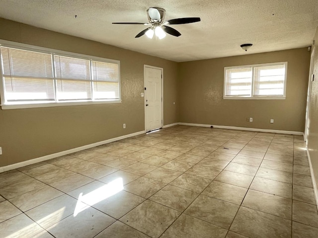 empty room with light tile patterned floors, a textured ceiling, and ceiling fan