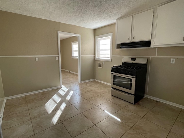 kitchen featuring stainless steel gas range oven, light tile patterned floors, white cabinets, and a textured ceiling