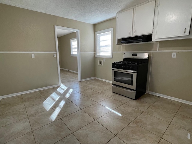 kitchen with light tile patterned flooring, white cabinets, and stainless steel gas stove